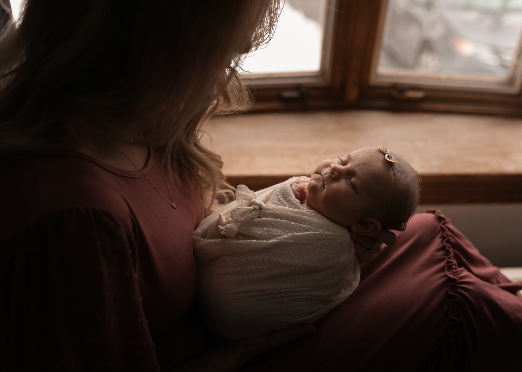 mom holding baby by window
