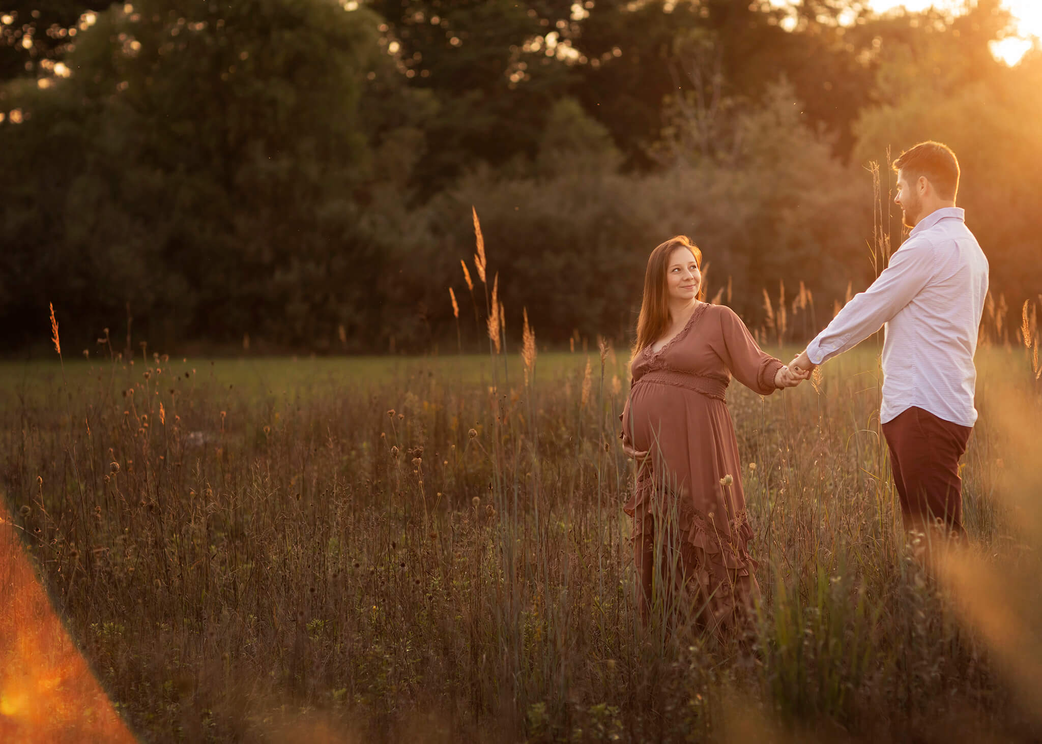 Husband and pregnant wife take a stroll through a field I Birth Centers in NJ