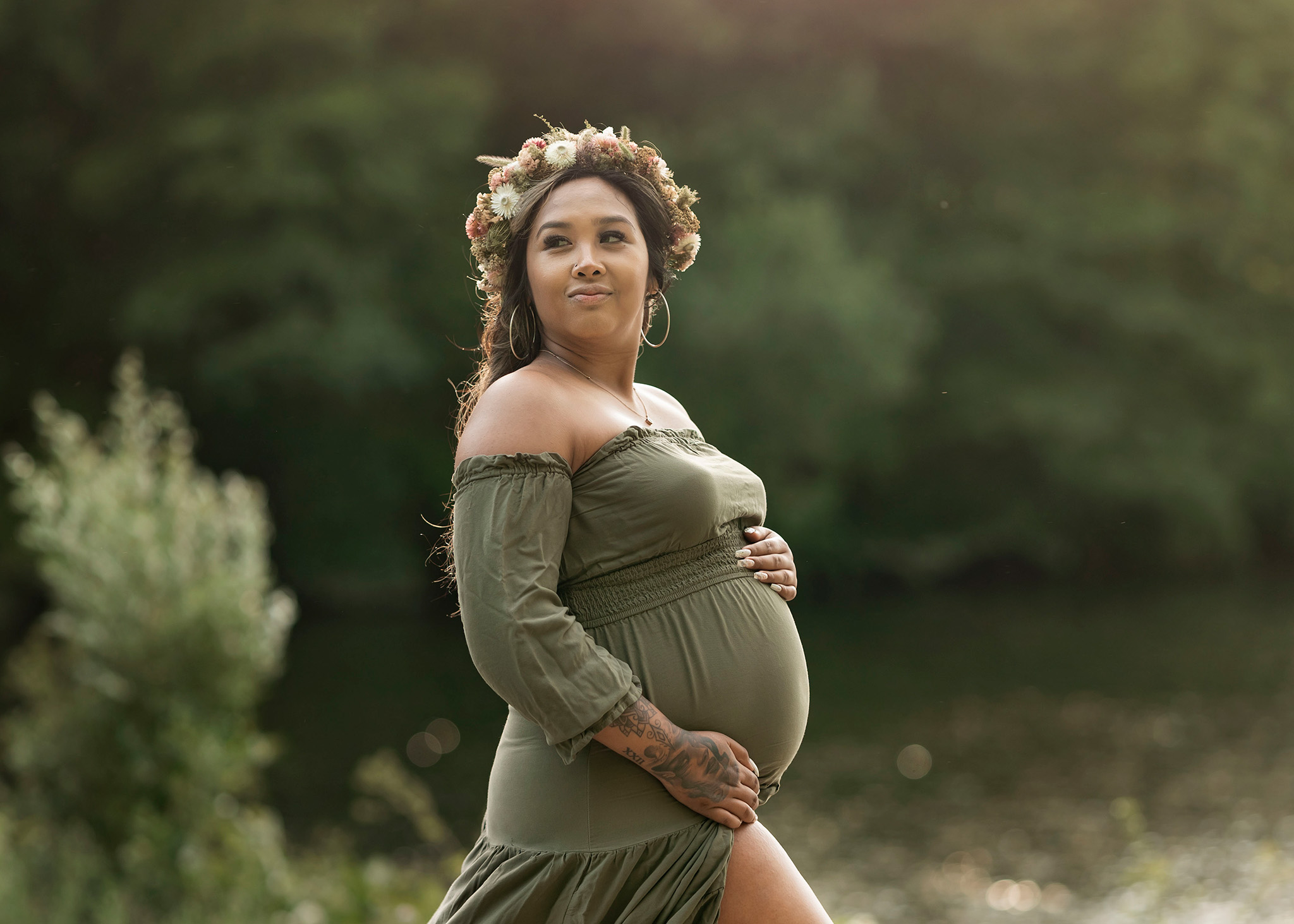 Expecting mom holds her belly and wear flower crown