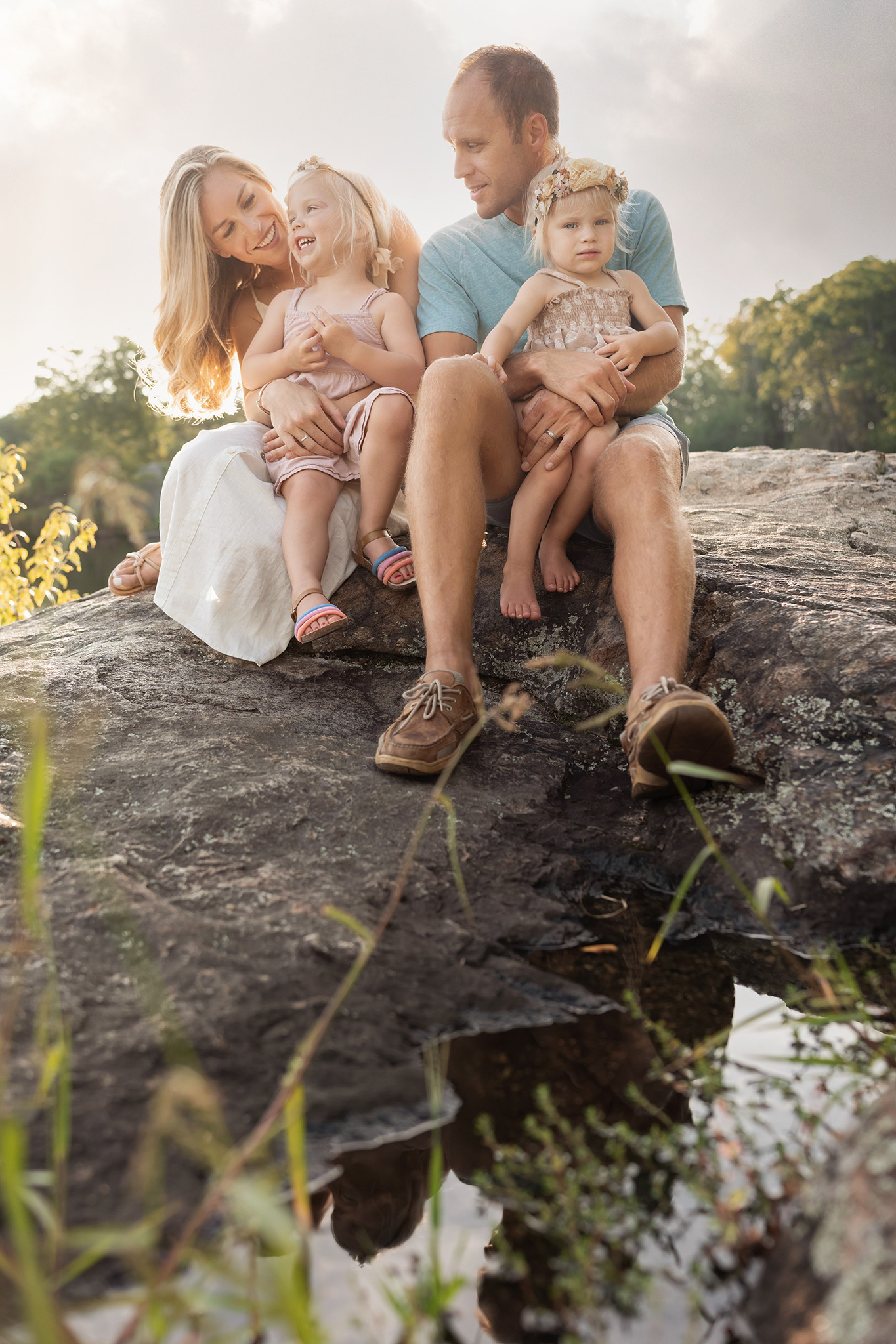 Family sits on a rock and laughs together during their family photography session