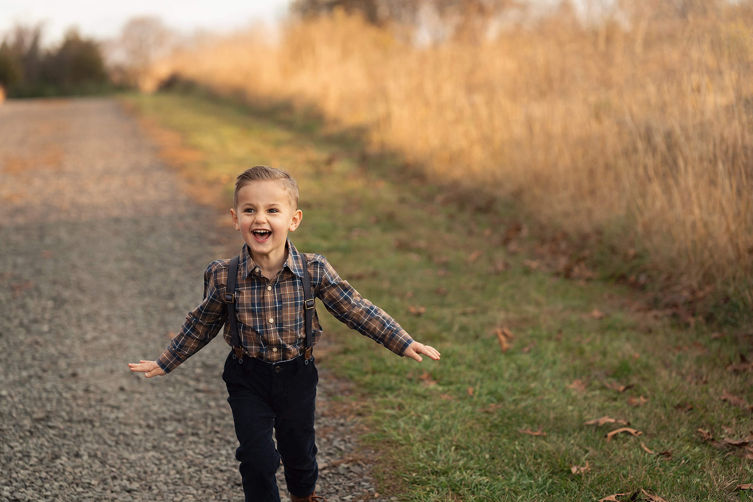 A happy toddler boy laughs while running through a park path at sunset