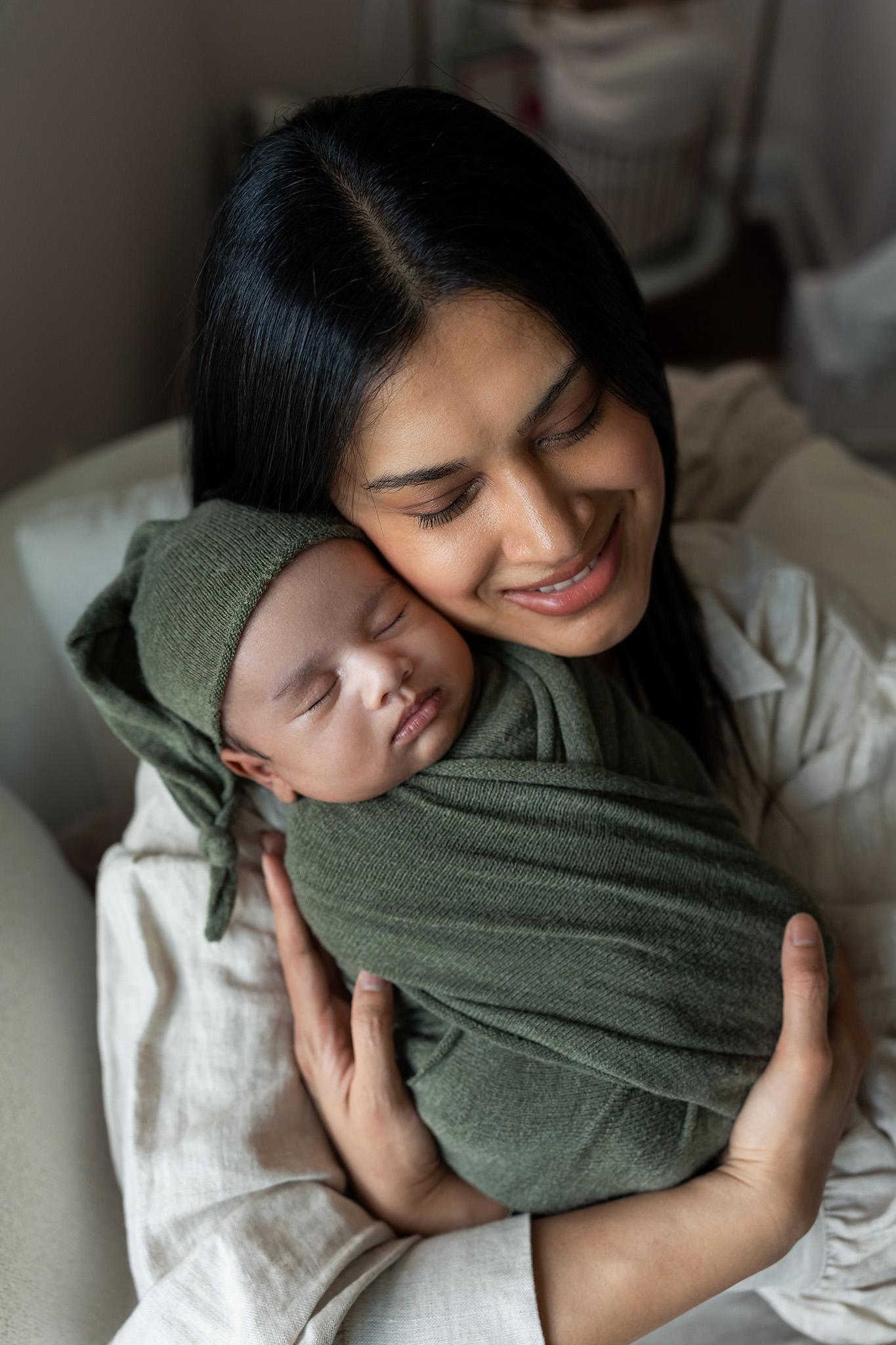 A happy new mom snuggles her sleeping newborn baby against her cheek before some pelvic floor therapy nj