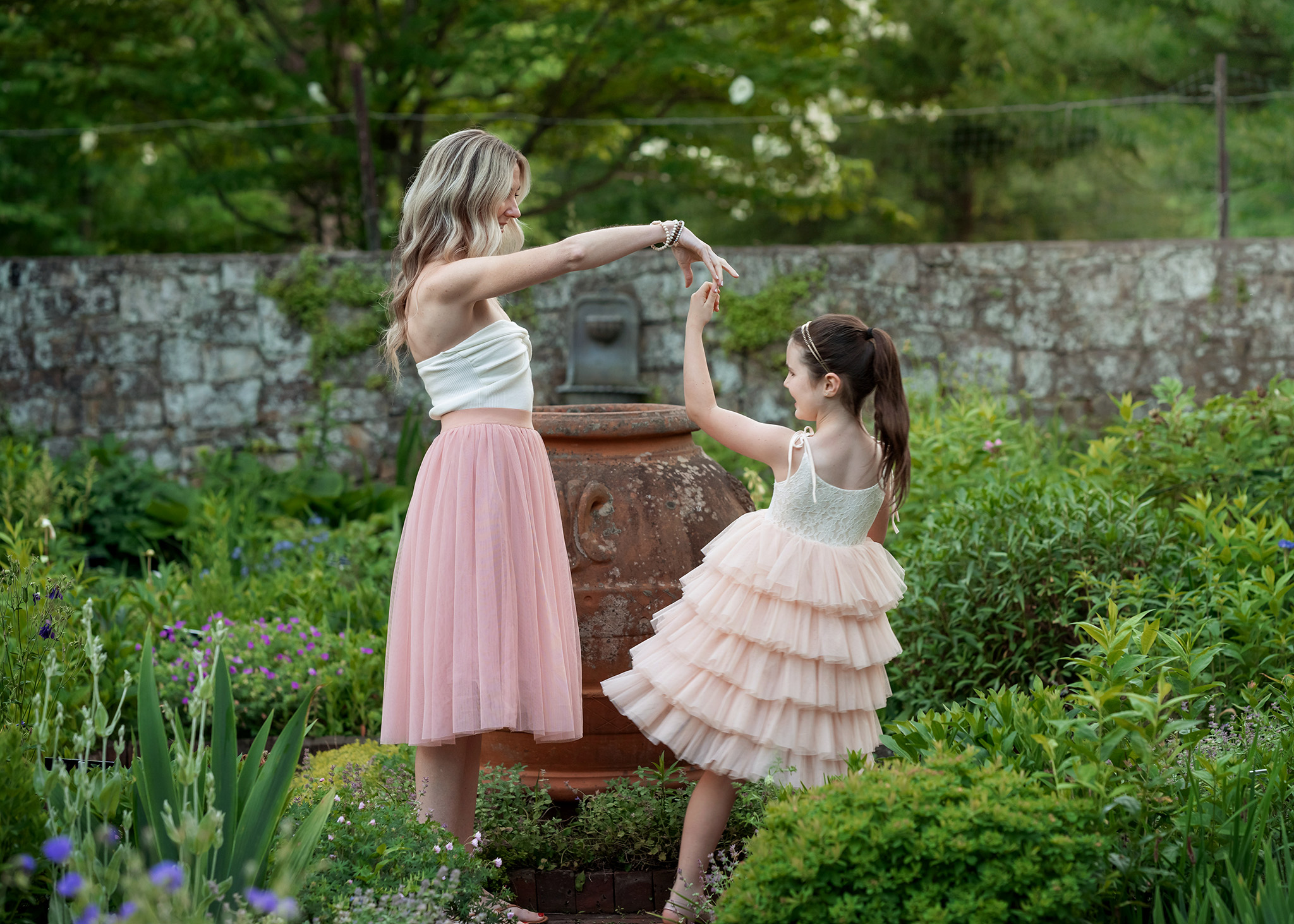 A mother dances and twirls her young daughter in pink tutus in a garden thanks to prenatal yoga morristown nj